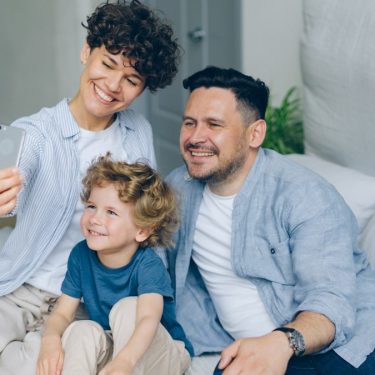 Perfect family girl guy and kid taking selfie at home in bed using smartphone